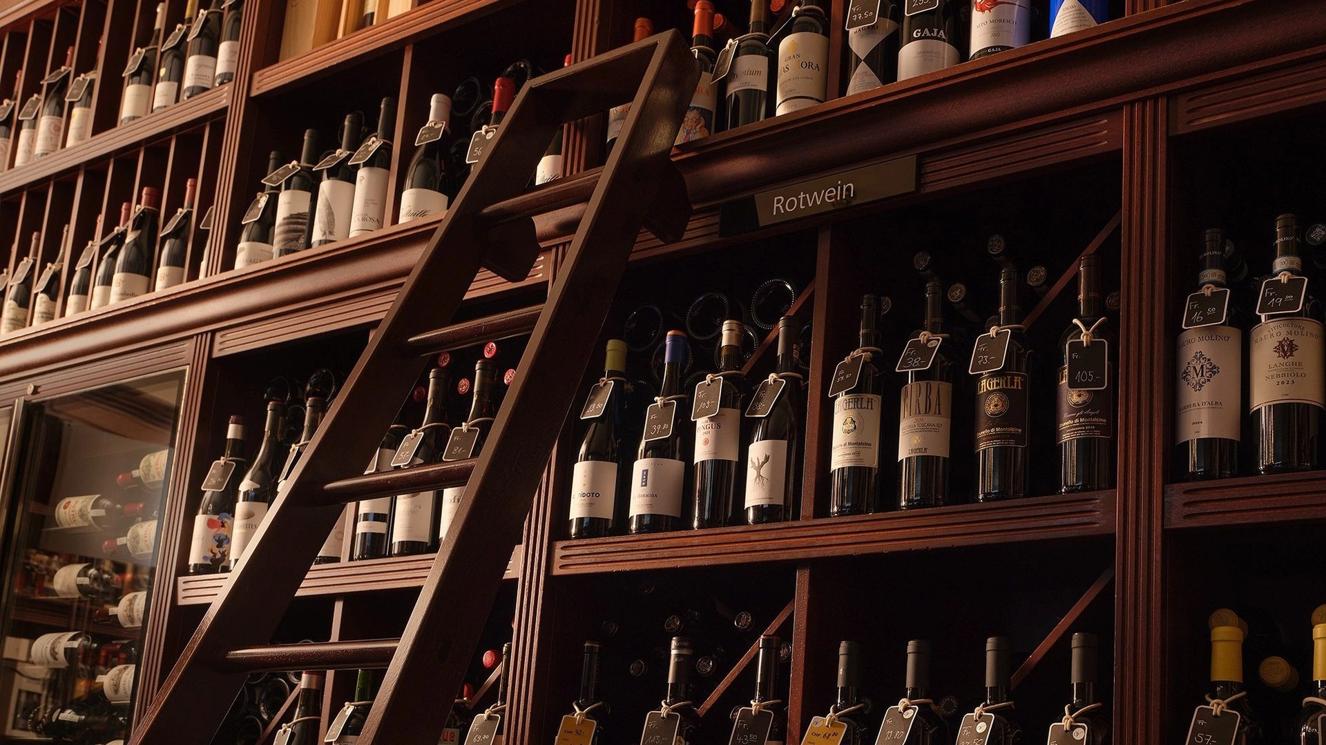 Shelves of wine to the ceiling, with a library ladder, at Baur au Lac Vins