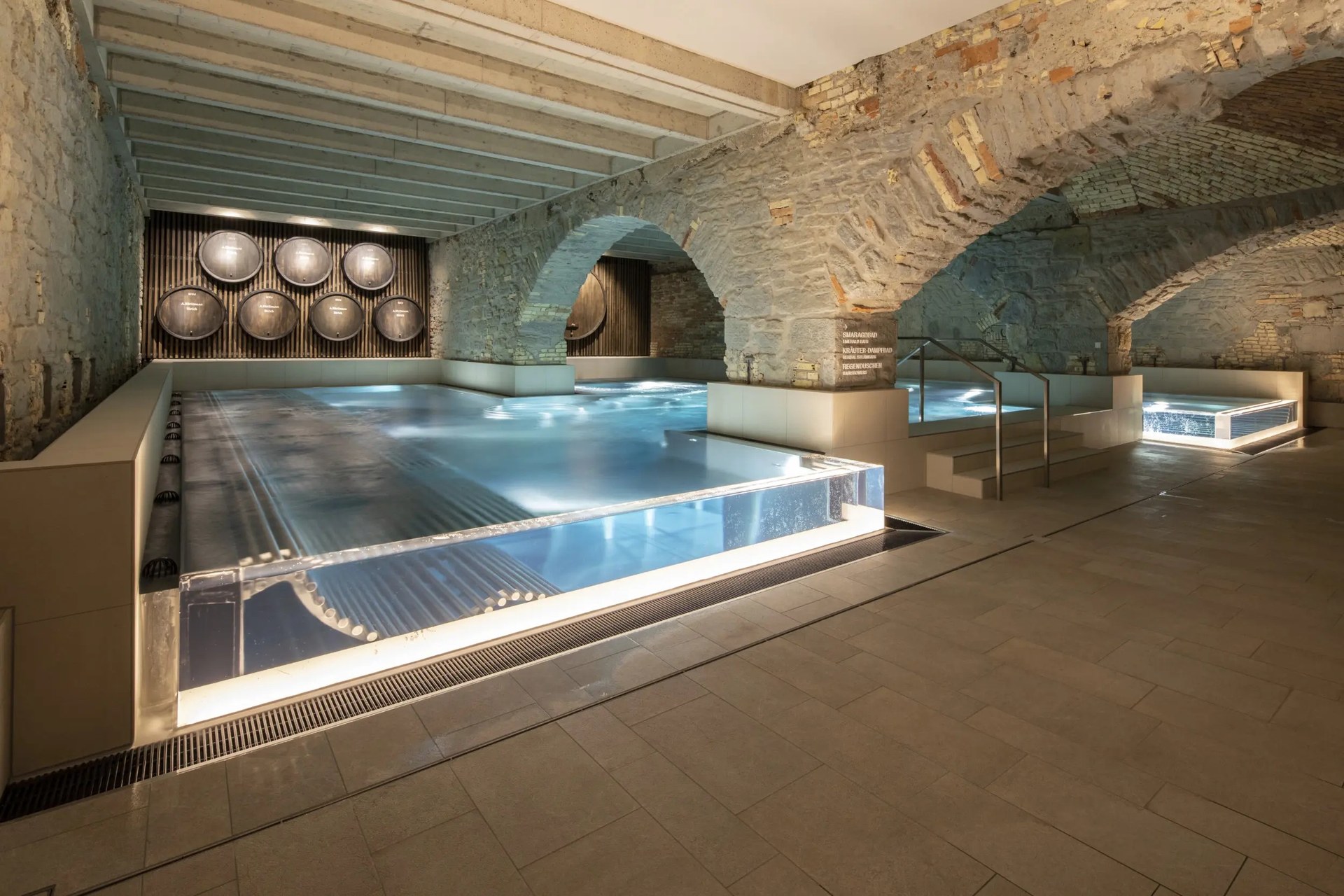 A glass-sided thermal pool under the brick vaults of the Hürlimannbad